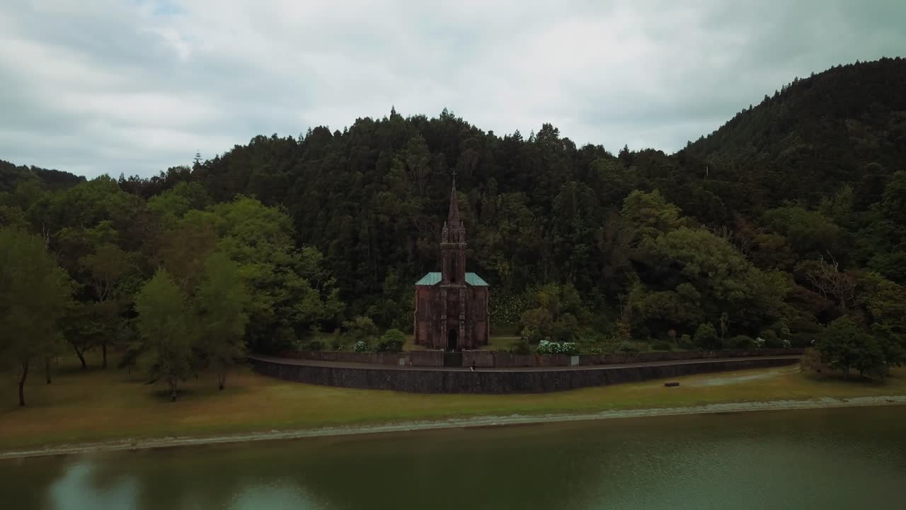 Aerial drone video of a hidden catholic church in the forest close to a lake in Azores volcanic islands.