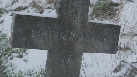 anonymous headstone inscribed with in loving memory, crucifix cross in snow covered graveyard