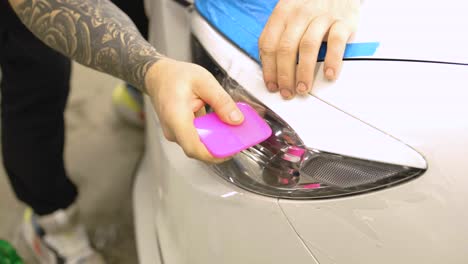 man covering car with vinyl polyurethane tape. films for the car. sticker protective film on the headlight of the car