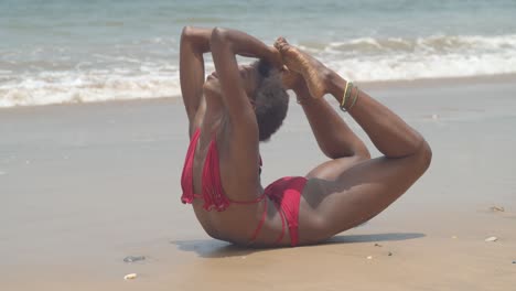 epic contortion pose of a bikini girl in the sand of an amazing beach location