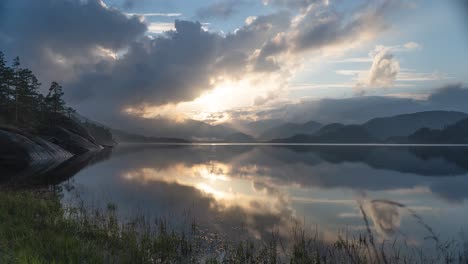 clouds, backlit by the setting sun, whirl in the sky and are reflected in the mirrorlike surface of the lake