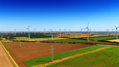 turbines dot the rolling fields. a landscape features numerous wind turbines operating in a green field under a clear blue sky during daytime