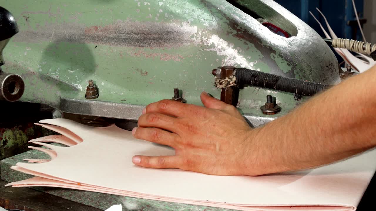artesano usando una máquina de corte de suelas mientras hace zapatos