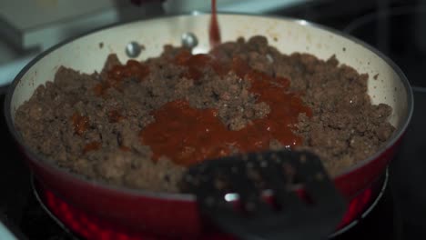 tomato sauce being poured on ground beef