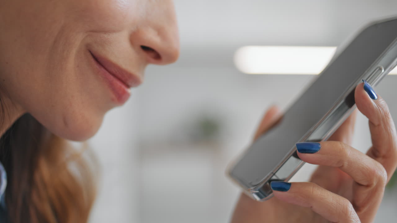 labios en primer plano hablando celda de micrófono. mujer joven sonriente sosteniendo teléfono inteligente