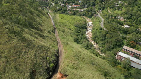 Establishing-Aerial-Drone-Shot-of-Train-Coming-up-Demodara-Loop-Train-Track-in-Sri-Lanka-on-Sunny-Day