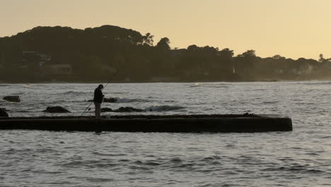 Fisherman-silhouette-fishing-on-a-pier,-jetty