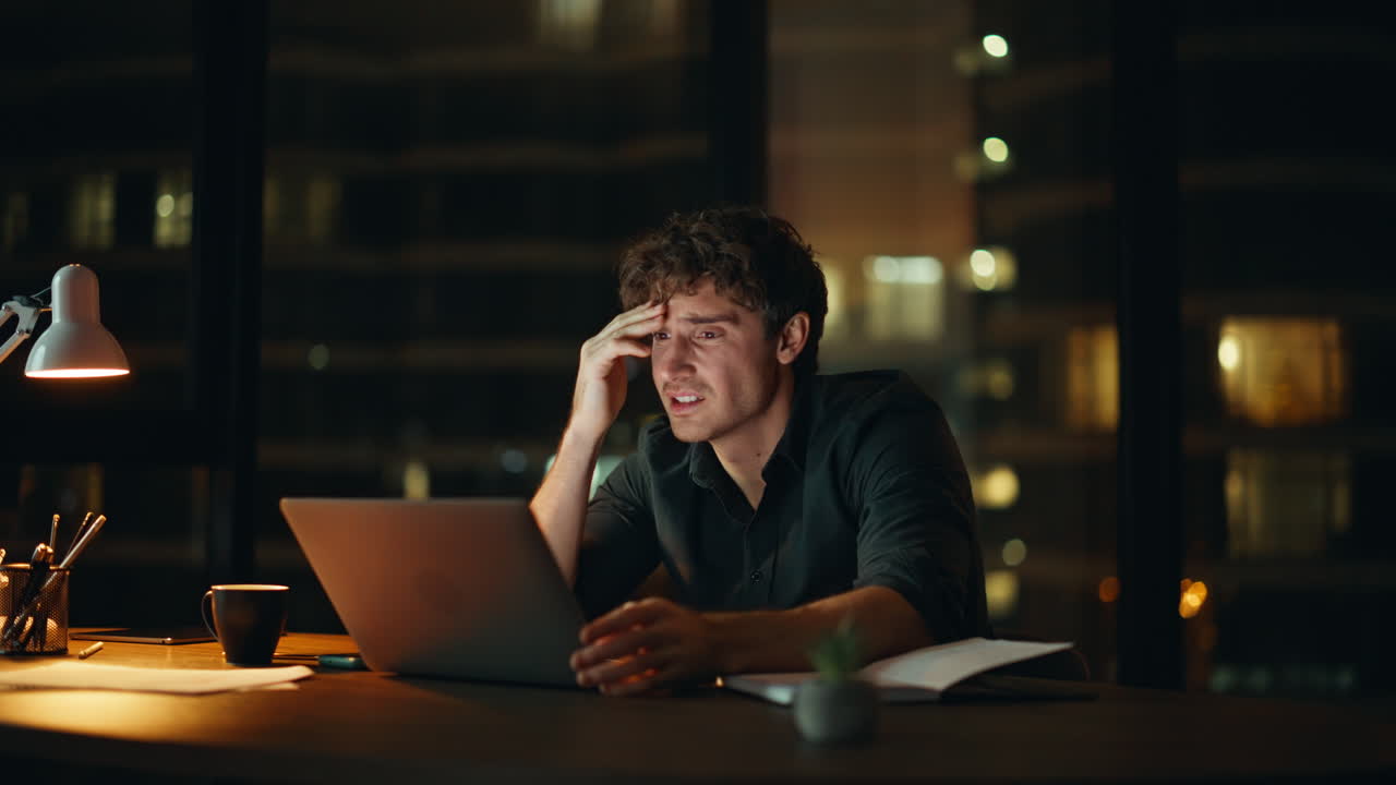 Troubled manager reading email with dismissal notice at dark office closeup