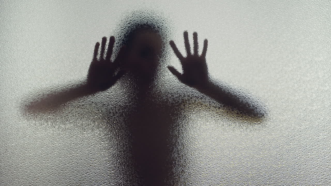 A female silhouette behind the frosted glass moves slowly
