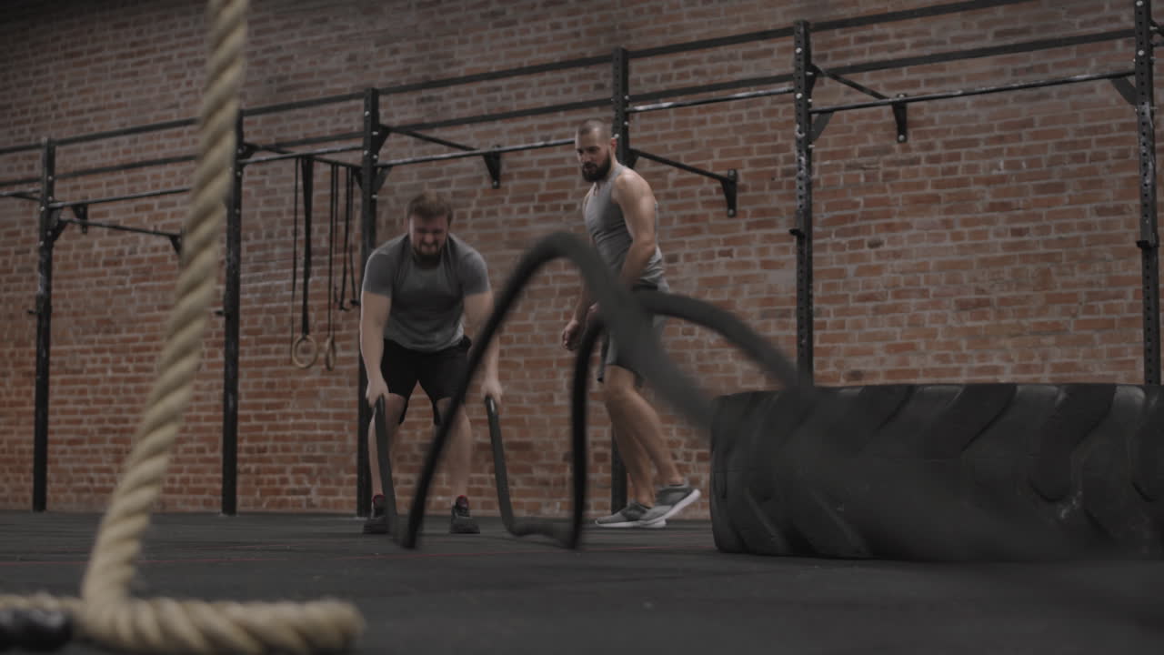 Coach Watching Man Doing Exercise with Battle Ropes