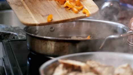 slomo shot of woman hand scraping bell peppers into cooking pan