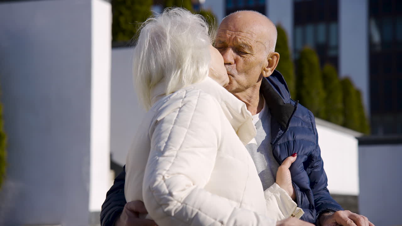 겨울날 공원에서 이야기하고 키스하는 노인 부부