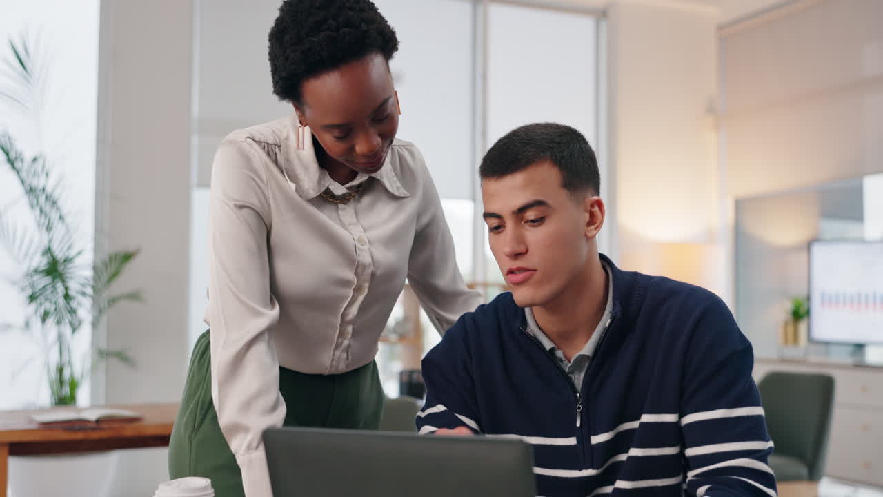 Two colleagues working together on a laptop in an office