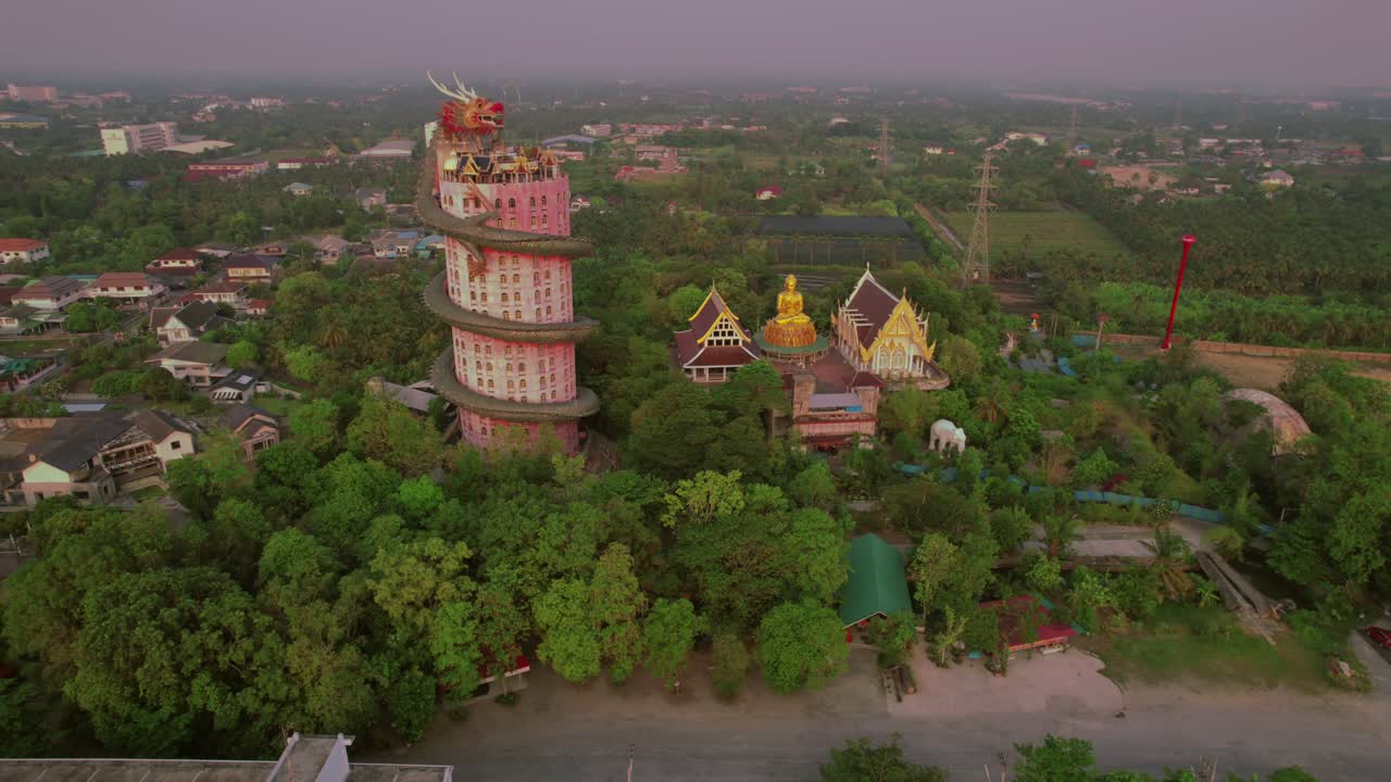 un templo colorido con una estatua de dragón al atardecer en un entorno tropical, rodeado de follaje vibrante, vista aérea