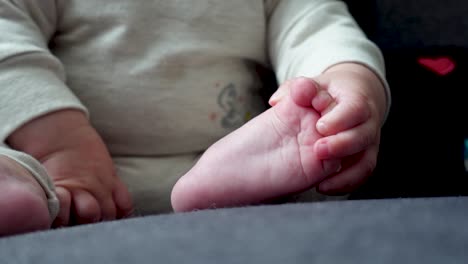 Infant-holding-toes-while-sitting-on-couch-in-the-sun