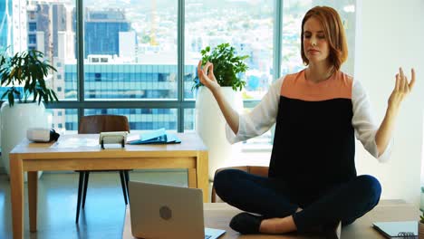 Female-executive-meditating-at-her-desk