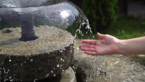 a woman's hand in the spray of water in the fountain 02