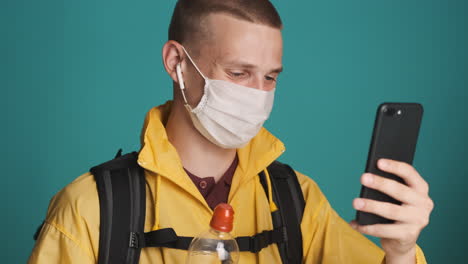 hombre con máscara protectora y botella haciendo una videocall