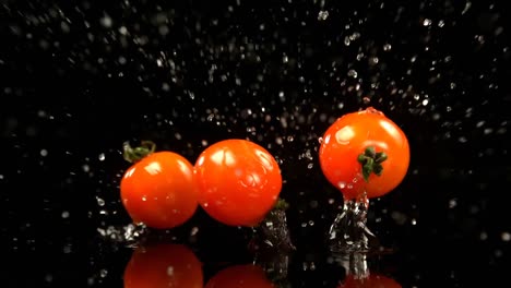 tomates cayendo en el agua contra un fondo negro 4k