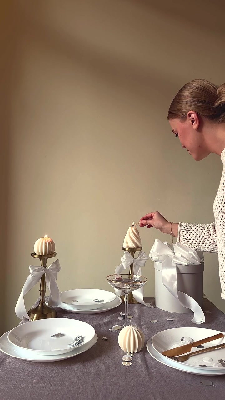 Donna che accende candele decorative su una tavola da pranzo apparecchiata