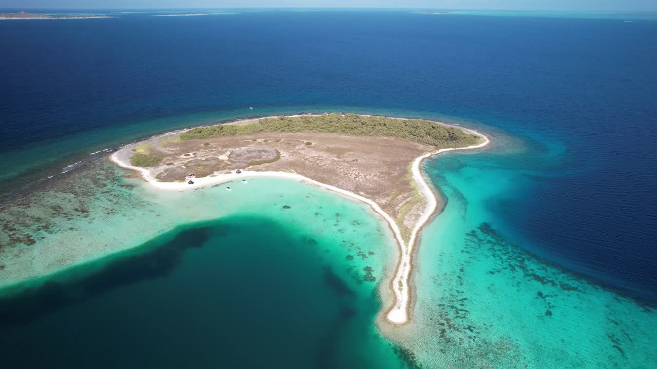 A small island with clear turquoise waters and a sandy shoreline in the caribbean, aerial view