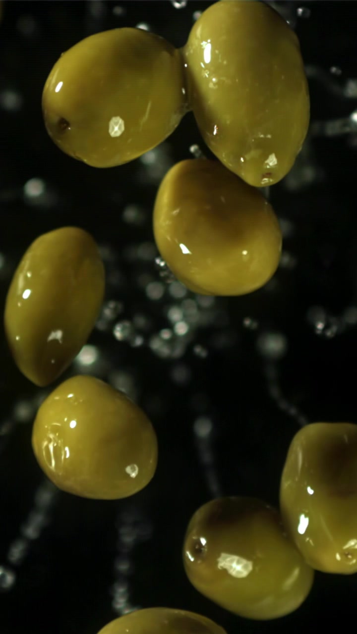 Olive verdi fresche in caduta al rallentatore con schizzi d'acqua