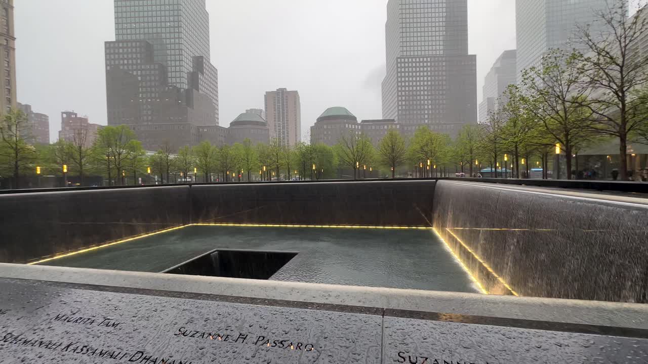 Rotating view of flowing waters in the pools of New York City's 911 Memorial and Museum on a rainy day
