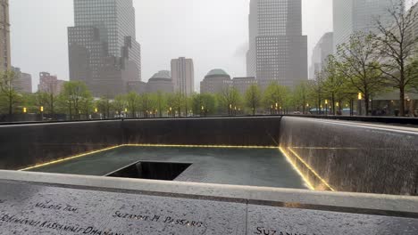 Rotating-view-of-flowing-waters-in-the-pools-of-New-York-City's-911-Memorial-and-Museum-on-a-rainy-day