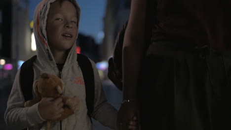 Niño-Caminando-En-La-Ciudad-De-Noche-Con-Mamá