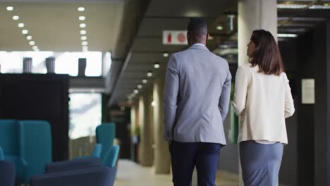 diverse businessman and businesswoman talking and walking in modern office