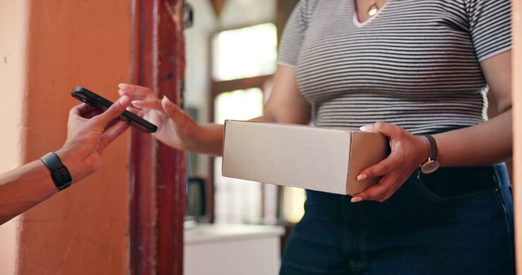 Addetto alle consegne che consegna un pacco al cliente sulla soglia di casa.