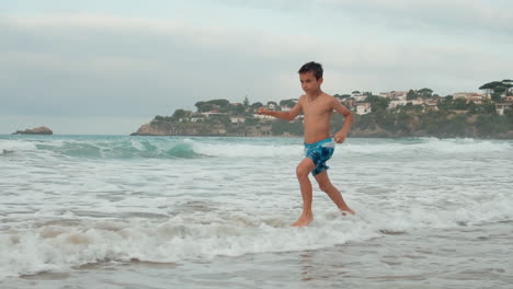 Happy-boy-enjoying-summer-vacation-at-seaside.-Active-guy-running-in-sea-surf.
