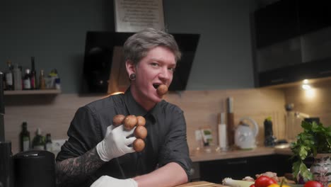 young crazy male chef in an elegant black shirt with an alternative look, tattoos holding mushrooms, looking in seductive way