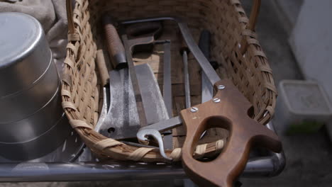 un cuchillo de carnicero, cubiertos y una sierra en una cesta