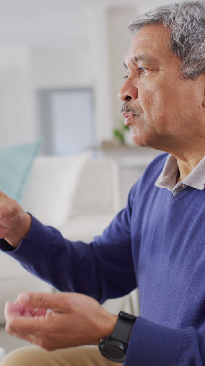 집에 앉아 약을 먹고 물을 마시는 노인 남성의 수직 비디오