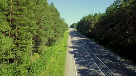 Aerial-Low-level-flying-over-the-highway-located-in-dense-forest-On-the-road-passing-cars-and-trucks