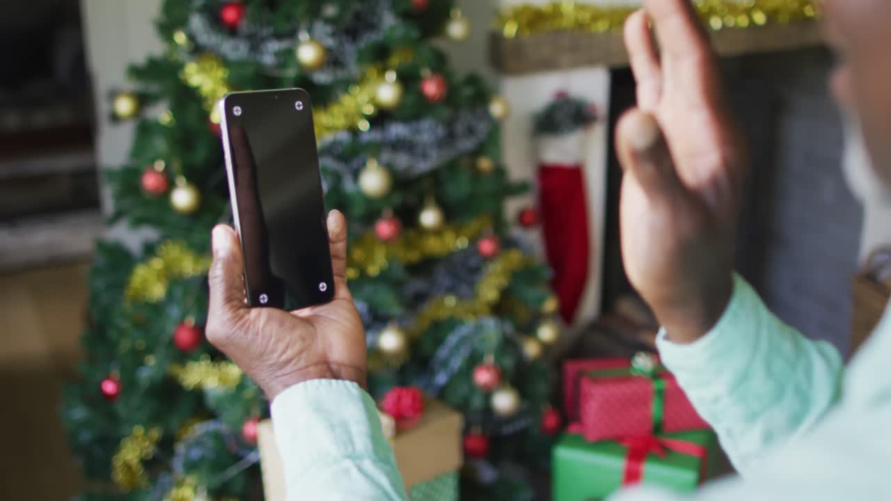 feliz mujer de edad avanzada de raza mixta en videollamada en un teléfono inteligente con espacio de copia en tiempo de navidad