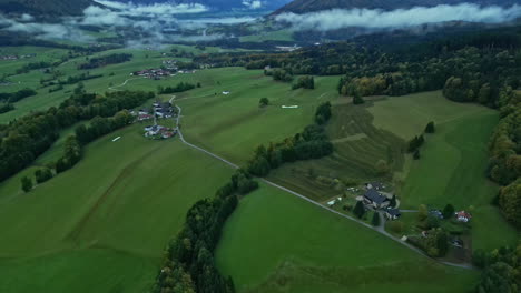 countryside with scattered houses, fields and distant misty mountains, overcast skies from aerial view