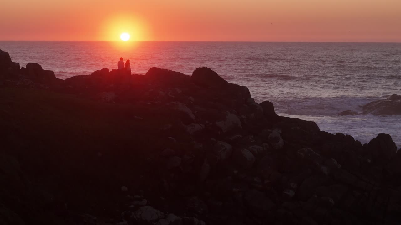 Couple watches the sunset near the ocean shot in slow motion 100 fps