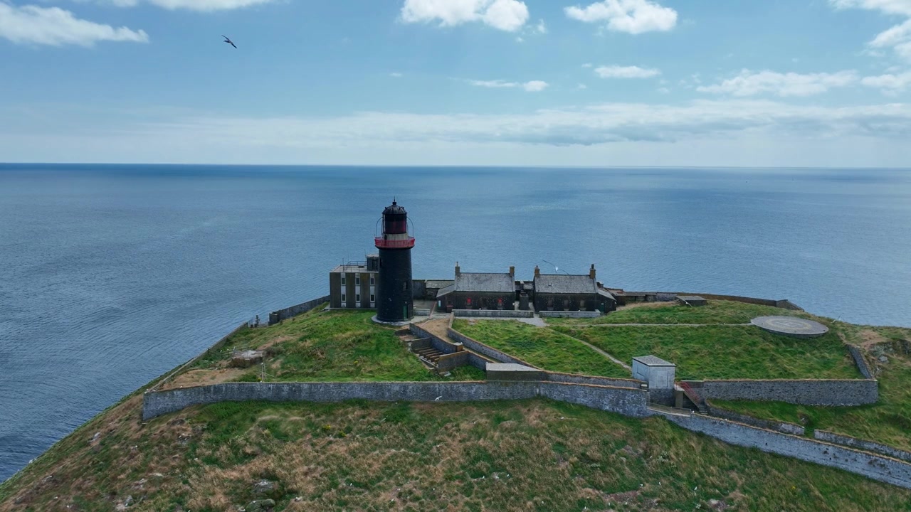Irlands episke steder: statisk billede af Black Ballycotton Fyr, County Cork, Irland, med det blå Atlanterhav og måger, der flyver rundt om dronen