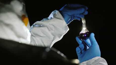 scientist holds a tube with a pink liquid