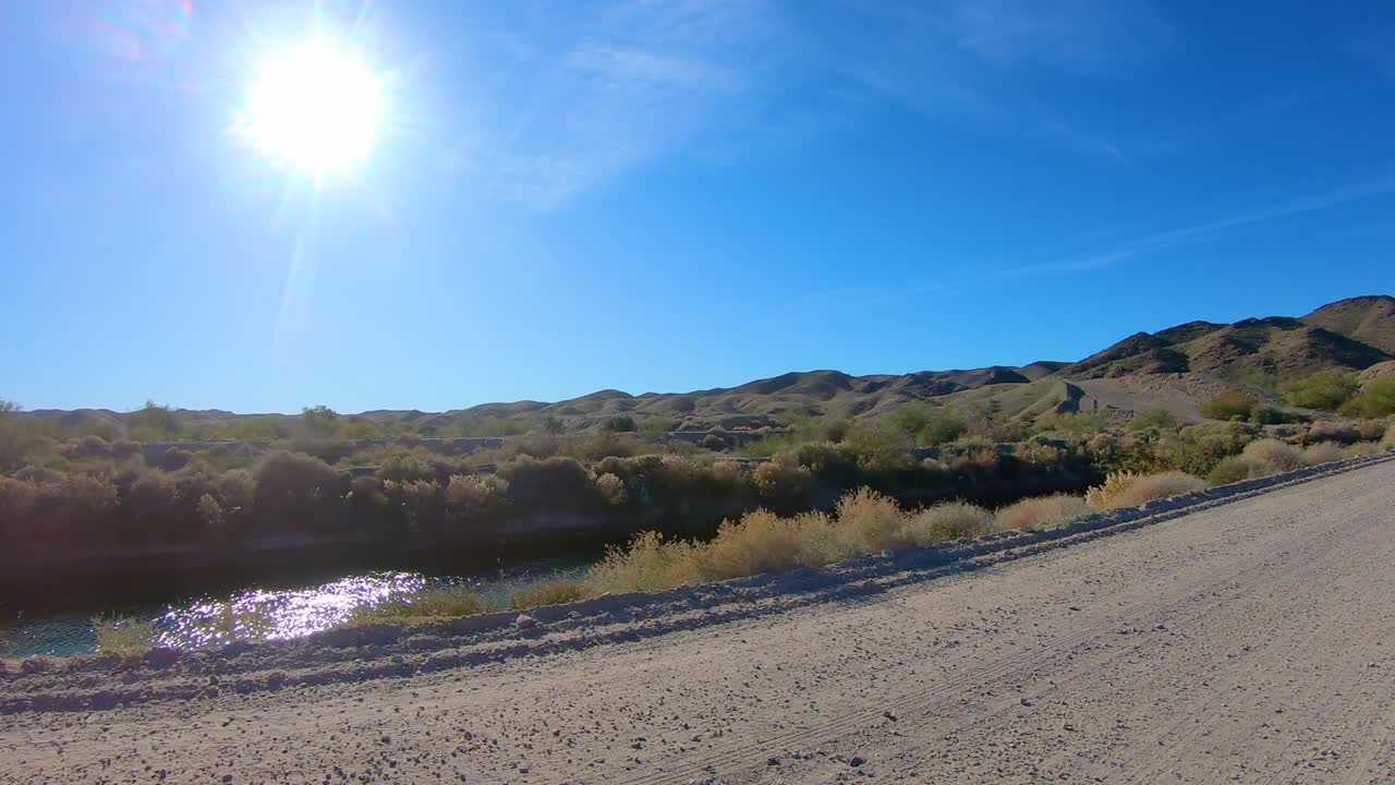 pov conduciendo por un camino de tierra a lo largo del canal de riego por gravedad de gila - yuma arizona