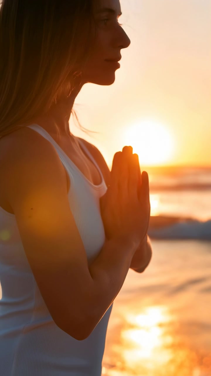Vista laterale di una donna vicino all'acqua del mare durante il tramonto, con le mani che si muovono verso il basso mentre la luce dorata si riflette sulle onde, con una morbida retroilluminazione, un'ambientazione tranquilla sulla spiaggia e una composizione naturale