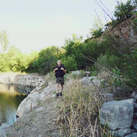 traveler is holding hands for the harnesses of a backpack and walking along the bank on the background of stones and rock. the tourist is looking at the wonderful landscape around him