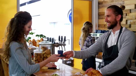 waiter serving coffee to female costumer at counter