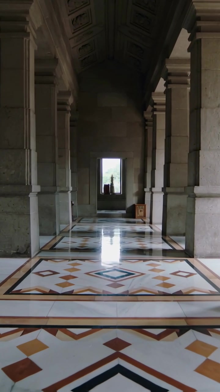 Video verticale: Carrello della telecamera che avanza lungo un corridoio colonnato, rivelando un pavimento piastrellato e una scatola.