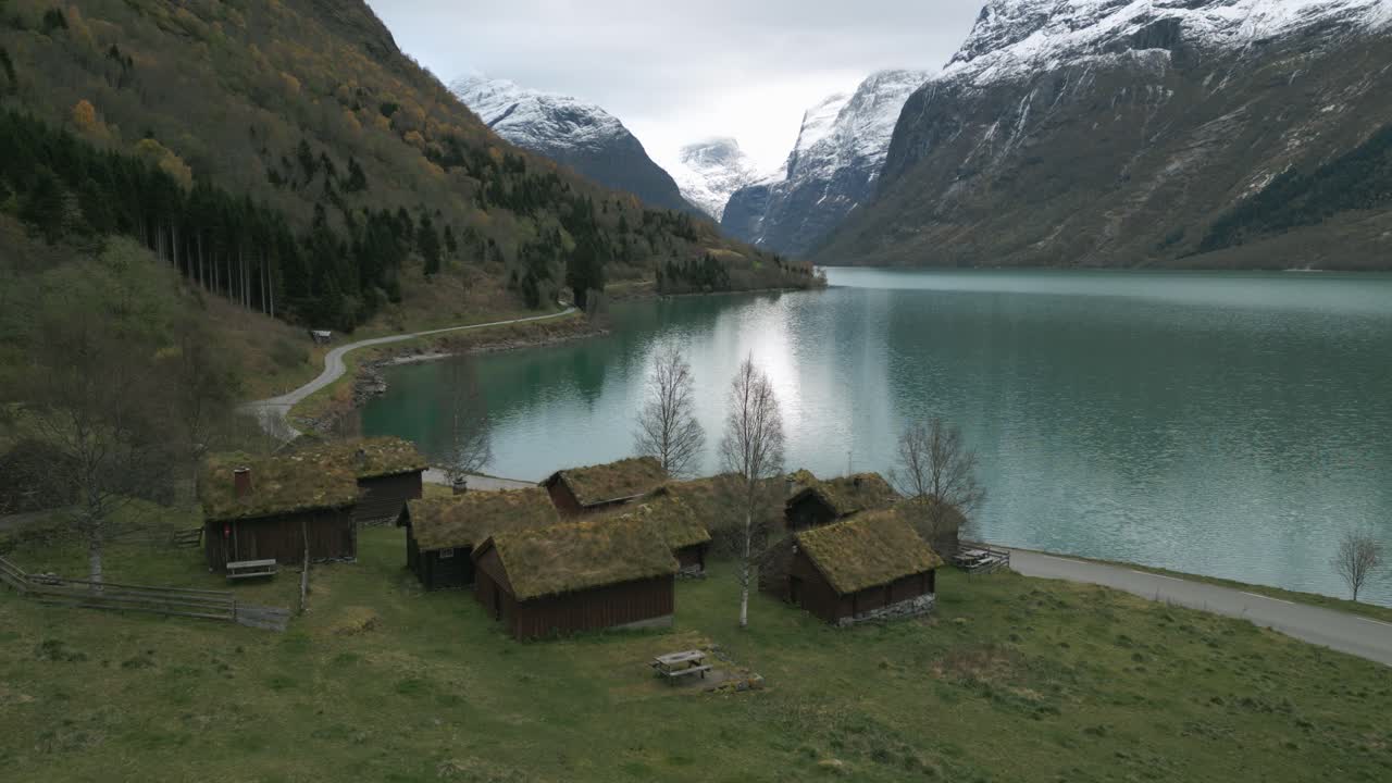 Tranquillo paesaggio scandinavo con tradizionali case con tetto in erba vicino al lago Lovatnet, Norvegia, colori autunnali