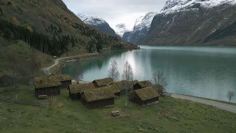 Tranquil-Scandinavian-landscape-with-traditional-grass-roofed-houses-by-Lovatnet-Lake,-Norway,-autumn-colors