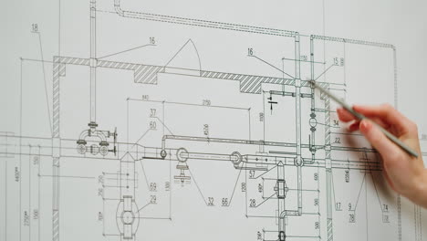 close-up of a hand pointing at an engineering blueprint