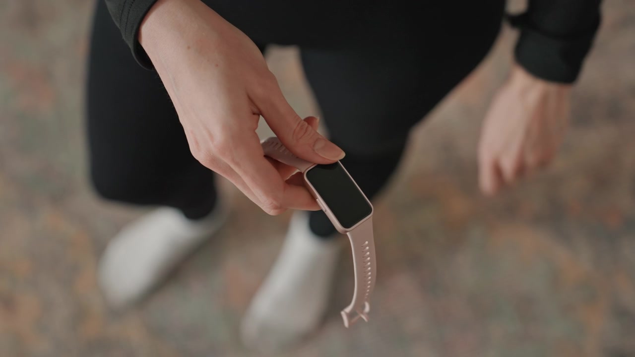 Caucasian woman fastening watch at home before workout, closeup of wrist and silicone band, focused prep for training session in living room, soft natural light, minimalist interior